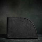 Front pocket wallet in black bison leather against a dark background.