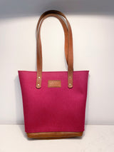 The Sheepscot Felt Wool Tote Bag, a stunning creation by Rogue Industries, boasts a pink wool body with elegant brown leather trim handles and bottom, prominently displaying the "Rogue Industries" label on a pristine white background.