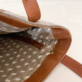 The image displays the inside of a Rogue Industries Sheepscot Felt Wool Tote Bag, showcasing a gray fabric lining adorned with a small dog pattern, equipped with two brass snaps and leather trim accents.