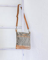 A small Ellis River Crossbody Bag by Rogue Industries hanging on a ladder.